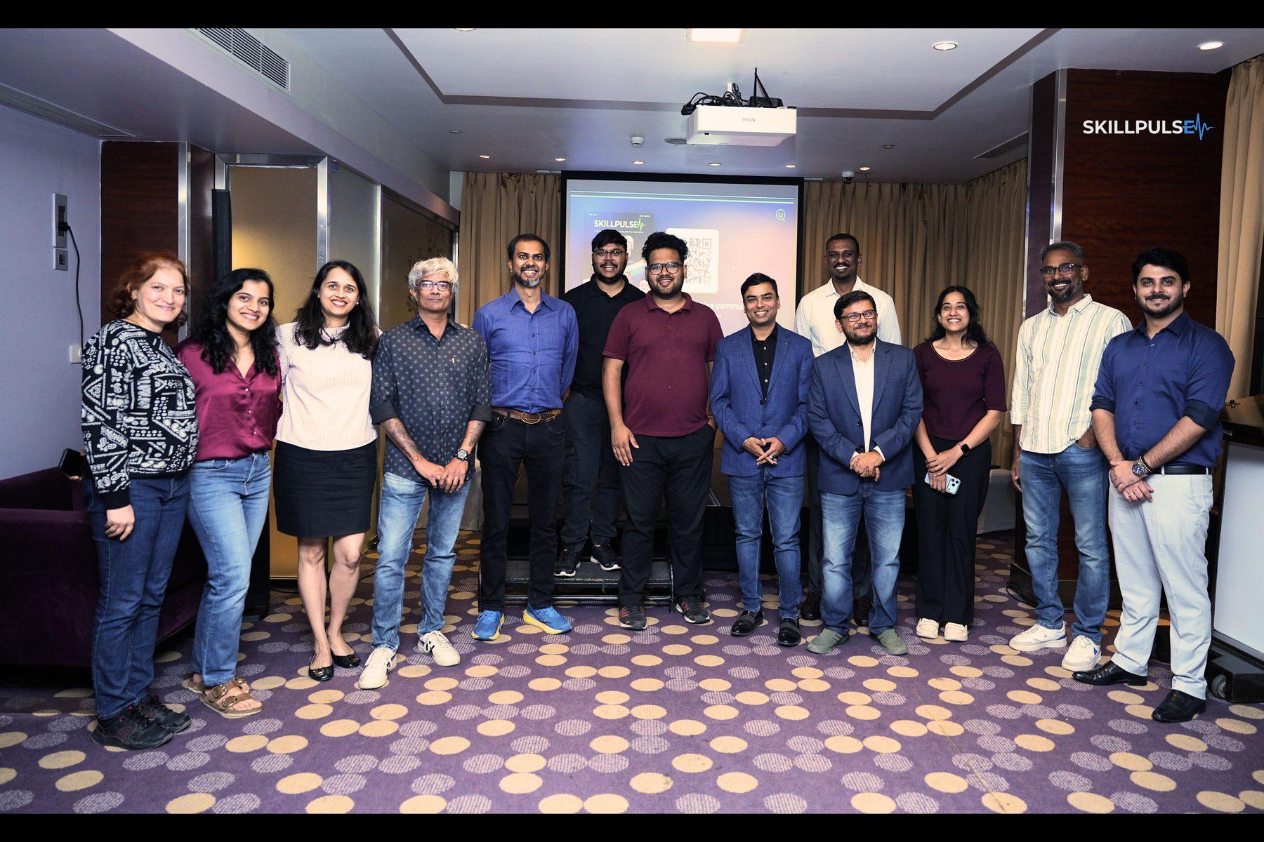 Speakers and attendees of the second SkillPulse Community Meet standing together at Novotel, Bengaluru, on 3 July 2026, with the SkillPulse presentation on screen behind them.